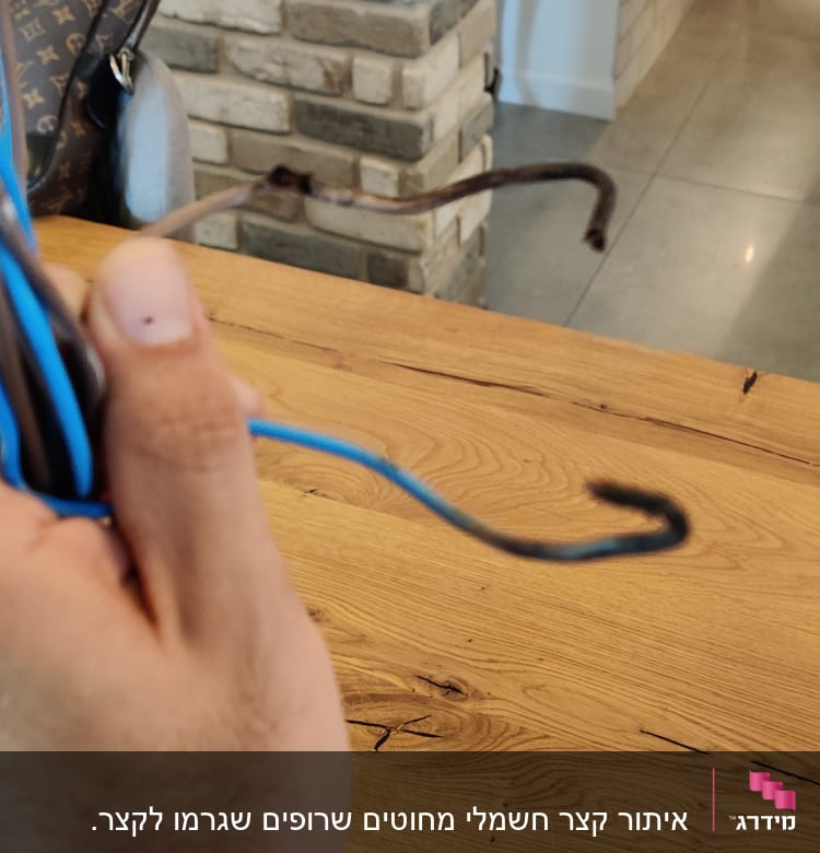 יד מחזיקה חוטי חשמל כחולים ושחורים